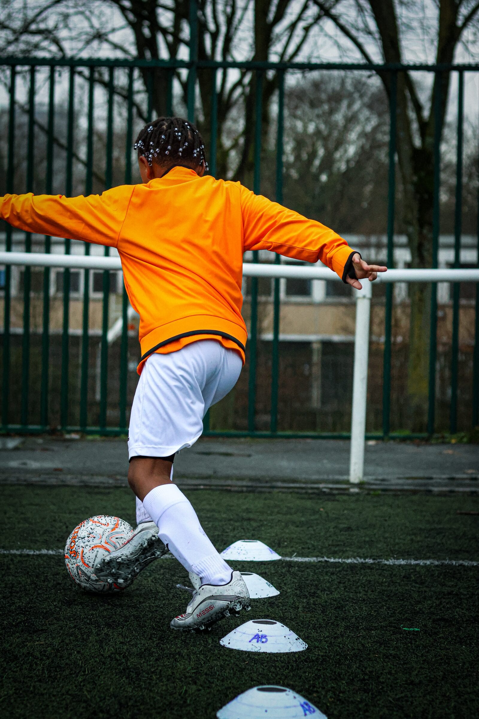 Jeune joueur de l'académie en dribble entre des plots à l'entraînement