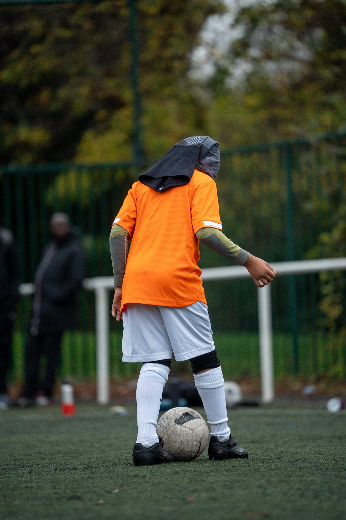Jeune joueur AB Football Académie, capuche relevée, ballon au pied