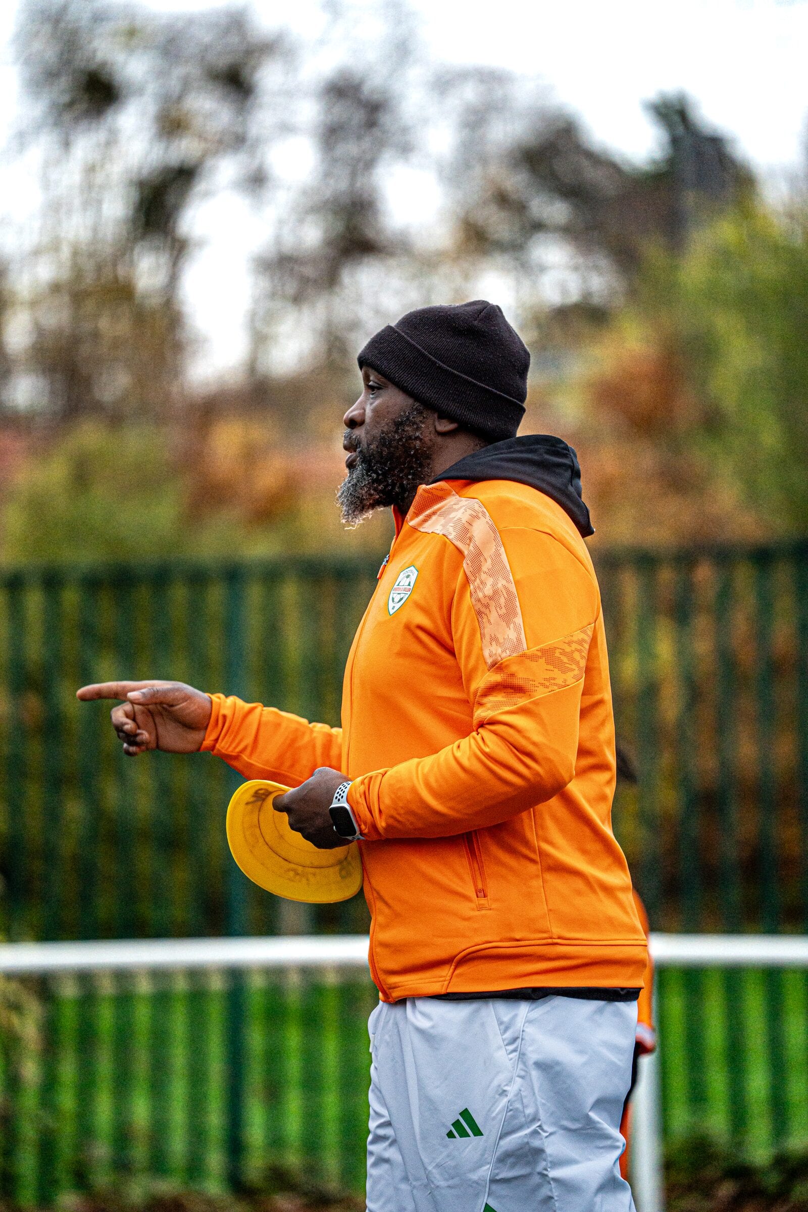Un éducateur AB Football Académie, en veste orange, donne des consignes sur le terrain